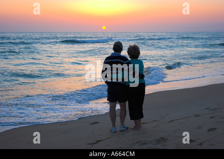 Middle aged couple embracing on a sandy beach at sunset. Stock Photo