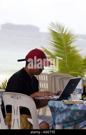 Filipino man from Manilla at his laptop computer on a working vacation ...