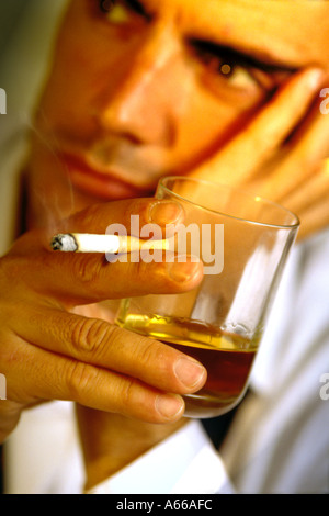 Portrait of a young depressive man drinking alcohol and smoking cigarette Stock Photo