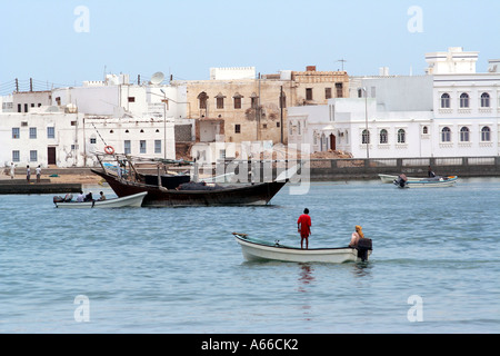 Motorboat, dhow and the village of Ayajh, Sur, Oman Stock Photo