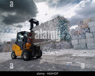 Forklift truck with clamping grip lifting a large bale of old used paper at a paper recycling factory in Cuijk the Netherlands Stock Photo