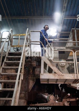 Paper factory worker standing on huge paper making machine in paper recycling plant in Cuijk the Netherlands Stock Photo