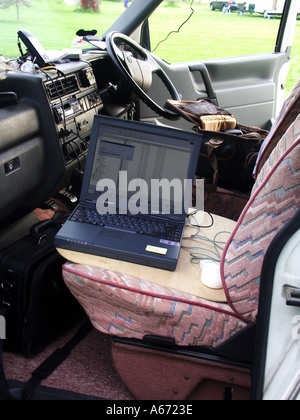 Professional photographer travelling and working on the road from mobile office showing front seats of camper van and laptop computer England UK Stock Photo