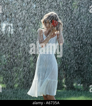 Girl walking alone in rain in park Stock Photo