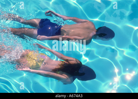 Couple swimming underwater in pool Stock Photo