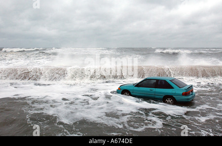 An abandoned car is stalled in flood waters as waves crash against the sea wall in Winthrop Massachusetts Stock Photo