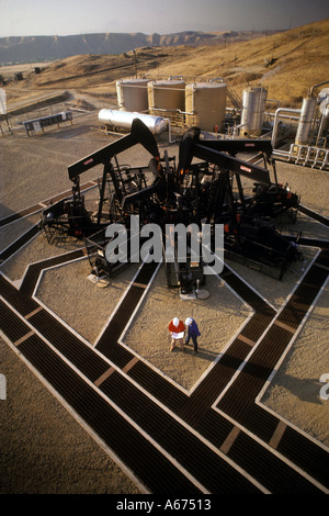 aerial view of technicians discussing data in front of five oil well pumps near Bakersfield California Stock Photo