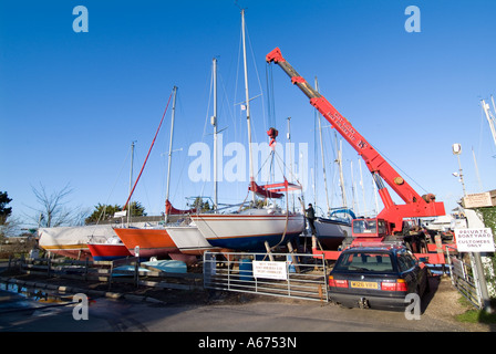 crane lifting a yacht out of the water and onto stilts in a marina Stock Photo