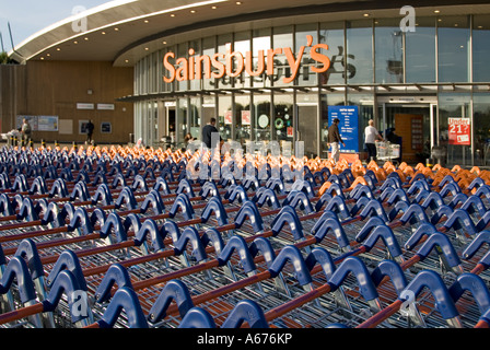 Large concentration of Sainsburys supermarket trolleys in front of store entrance Stock Photo