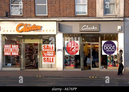 Two adjacent high street shop windows with January sales banner posters including half price offers Stock Photo