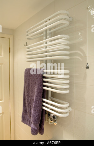 Bathroom shower room central heating towel rail tubes for room heating & towels warm & dry fixed to white glazed wall tiles light pull cord England UK Stock Photo