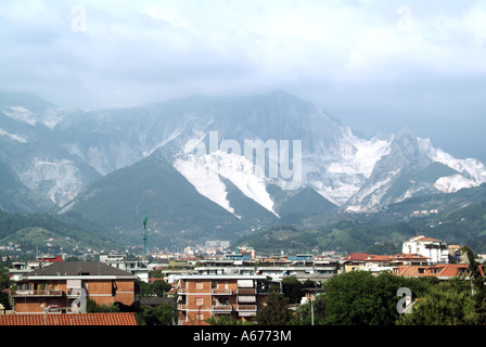 Residential areas below a summer view of white quarry workings in Apuan Alps producing famous Carrara marble for sculpture & buildings Tuscany Italy Stock Photo