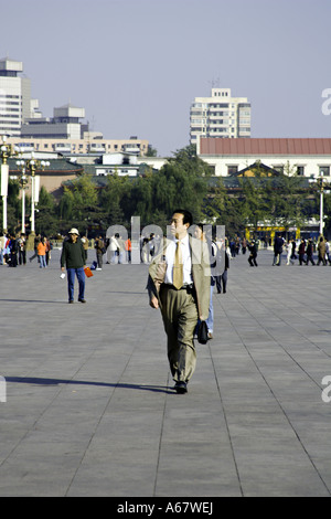 CHINA BEIJING Chinese businessman wearing a suit and tie and carrying a briefcase walks through Tiananmen Square Stock Photo