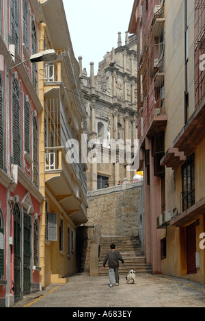 Young boy walking with a dog in a street behind the ruins of 17th-century Portuguese church of St Paul's in Santo António, Macau, China Stock Photo