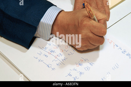 Man writing with pen in Chinese text on white paper Stock Photo