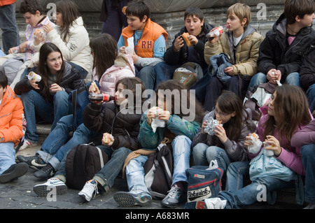 Young schoolchildren eating sandwiches in a piazza, Rome Italy Stock Photo