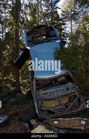 Ripped car frame leaning to tree in forest , Finland Stock Photo