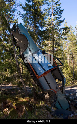 Ripped car frame leaning to tree in forest , Finland Stock Photo