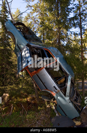 Ripped car frame leaning to tree in forest , Finland Stock Photo