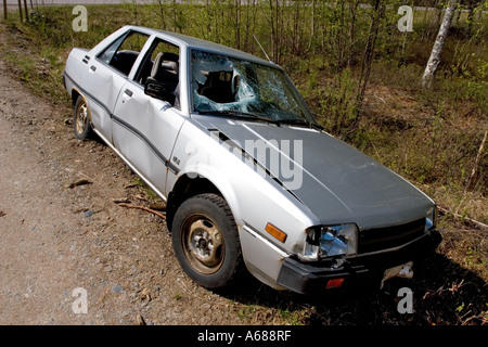 Silver colored, abandoned and vandalised sedan at roadside on a side-road , Finland Stock Photo