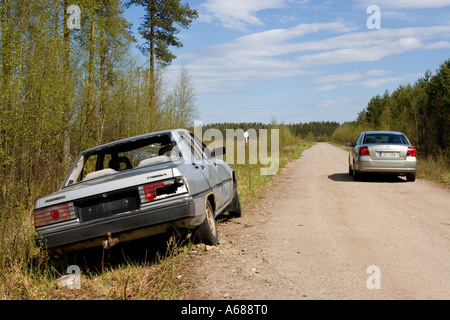 Silver colored abandoned and vandalised sedan at roadside on a side-road , Finland Stock Photo