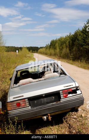 Silver colored abandoned and vandalized sedan at roadside on a side-road , Finland Stock Photo