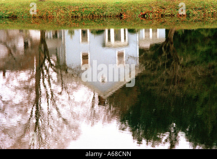 Reflection of wooden clapperboard house in water of a lake, New England. Lakeville, Connecticut, USA. Stock Photo