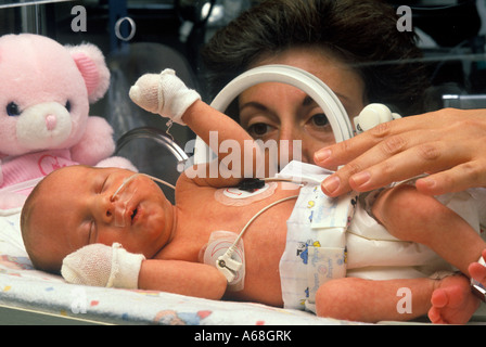 Nurse attends premature infant in an incubator in neonatal intensive care unit NICU Stock Photo