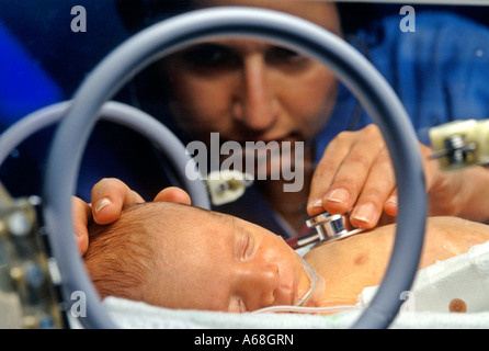 Nurse attends premature infant in an incubator in neonatal intensive care unit NICU Stock Photo