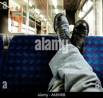 Man sitting with his feet up in a London Underground train. Stock Photo