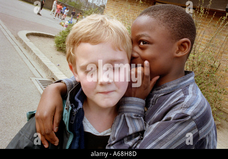 Two boys whispering a secret to each other at break time in primary school. Stock Photo