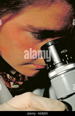 Woman looking through a microscope Stock Photo