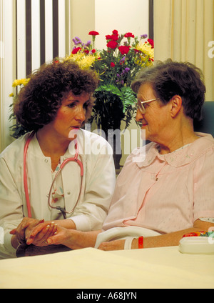 Nurse talks with elderly female patient in her hospital room Stock Photo