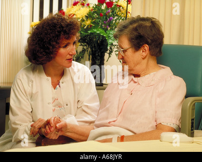 Nurse talks with elderly female patient in her hospital room Stock Photo