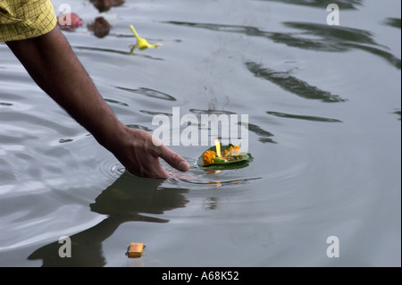 man putting a lit candle in the water of the sacred lake of Grand Bassin Stock Photo