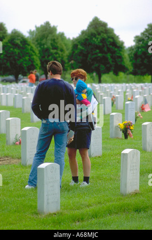 Family age 22 and 1 remembering fallen soldier on Memorial Day. Fort Snelling Military Cemetery Minneapolis Minnesota USA Stock Photo