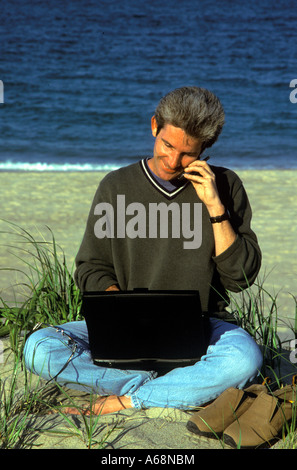 Man working on a laptop computer while at the beach Stock Photo