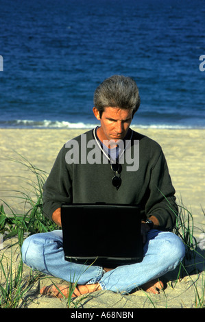 Man working on a laptop computer while at the beach Stock Photo