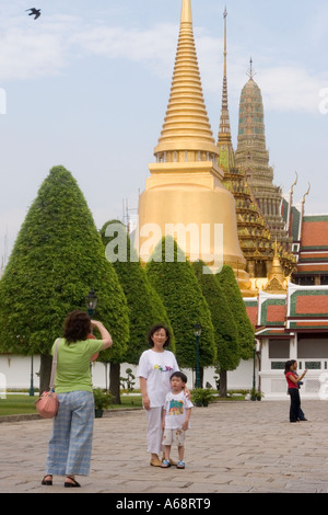 Asian tourists at the Grand Palace Complex in Bangkok with The Phra Sri Ratana Chedi dominating the background Stock Photo