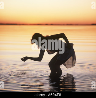 silhouette of girl wading nude in lake at sunrise Stock Photo - Alamy