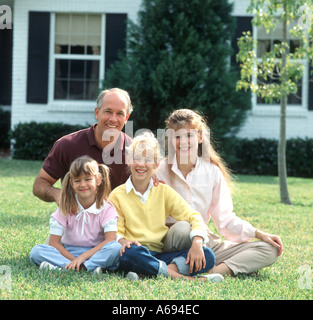 Family of four posing on lawn Stock Photo