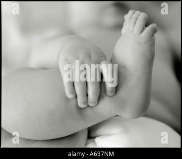 Baby holding leg with small hands. Stock Photo