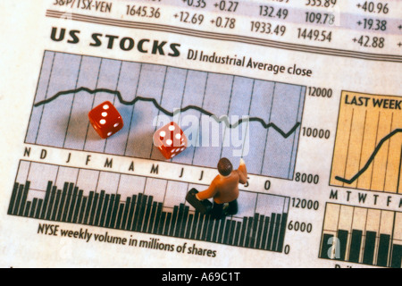 Toy businessman figurine standing on stock market pages with pair of dice Stock Photo