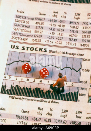 Toy businessman figurine standing on stock market pages with pair or dice Stock Photo