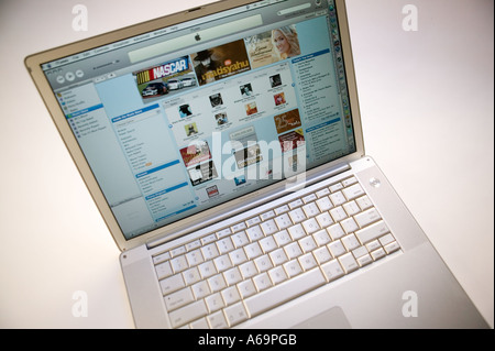 Apple laptop powerbook computer on white background displaying page from iTunes online music and video store website Feb 2006 Stock Photo