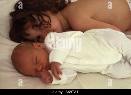 Newborn baby sleeping next to older sister Stock Photo