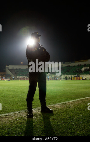 Silhouette of a policeman watching a football game Stock Photo