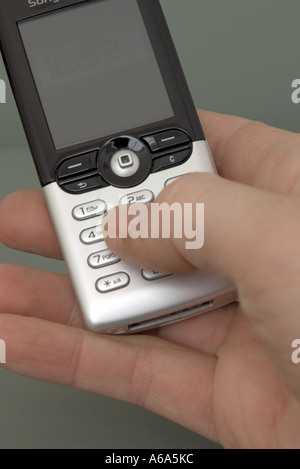 man keying into silver mobile phone using thumb Stock Photo