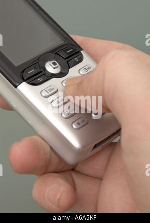 man keying into silver mobile phone using thumb Stock Photo