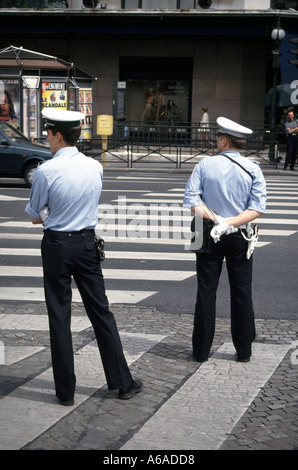 Paris street scene back view French police in uniform on traffic duty at pedestrian crossing road markings sunny sunshine spring day in1900s France Stock Photo